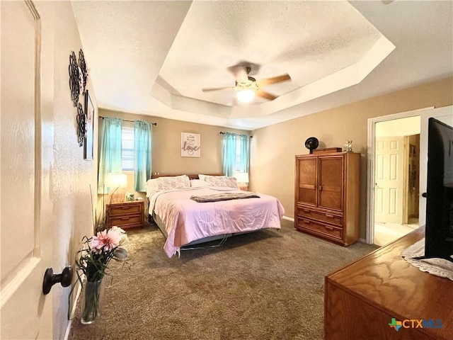 bedroom with a tray ceiling, carpet floors, a textured ceiling, and a ceiling fan