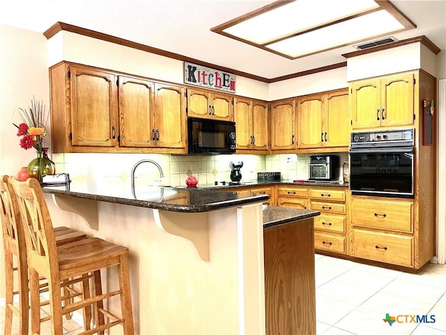 kitchen featuring decorative backsplash, a breakfast bar area, a peninsula, and black appliances