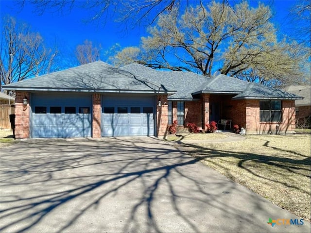 single story home with brick siding, concrete driveway, an attached garage, and a shingled roof