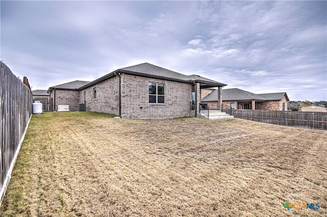 rear view of property featuring central AC and a yard