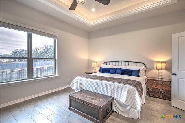 bedroom featuring a raised ceiling, ceiling fan, and light hardwood / wood-style floors