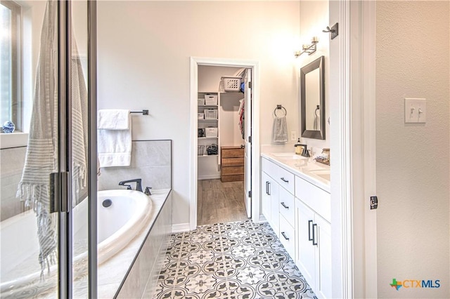 bathroom featuring vanity, tile patterned floors, and tiled bath