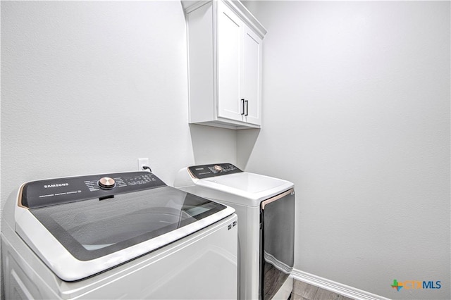 washroom with independent washer and dryer, hardwood / wood-style floors, and cabinets