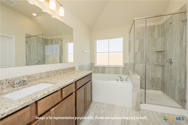 bathroom featuring shower with separate bathtub, vanity, and vaulted ceiling