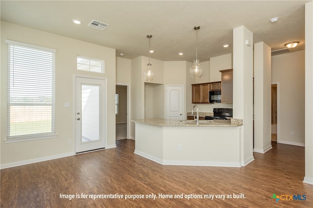 kitchen with hanging light fixtures, dark hardwood / wood-style flooring, black appliances, and light stone countertops