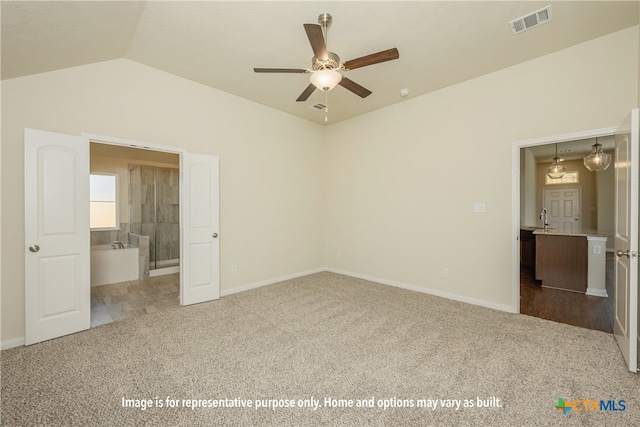 unfurnished bedroom with vaulted ceiling, sink, ensuite bathroom, carpet, and ceiling fan