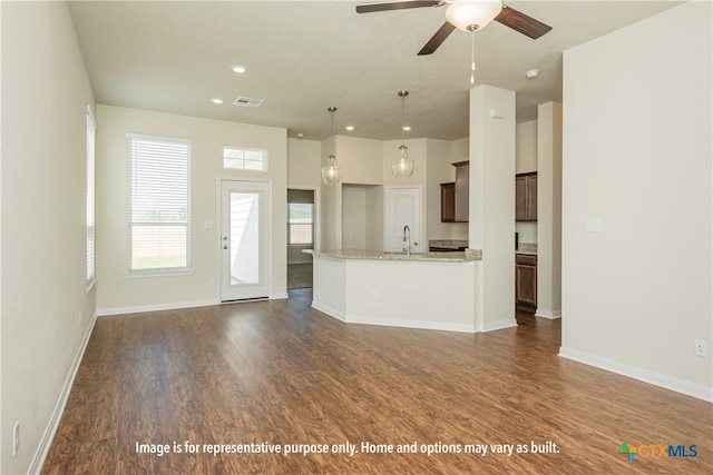 kitchen with sink, light stone countertops, ceiling fan, hanging light fixtures, and dark hardwood / wood-style flooring