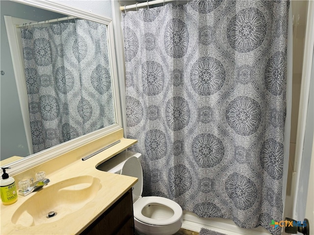 bathroom with curtained shower, vanity, and toilet