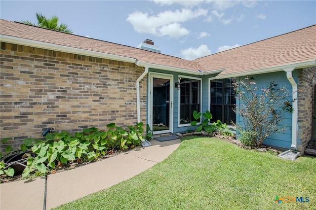 505 Cabana Dr, Victoria, TX 77901 - property entrance with a lawn, a chimney, brick siding, and roof with shingles