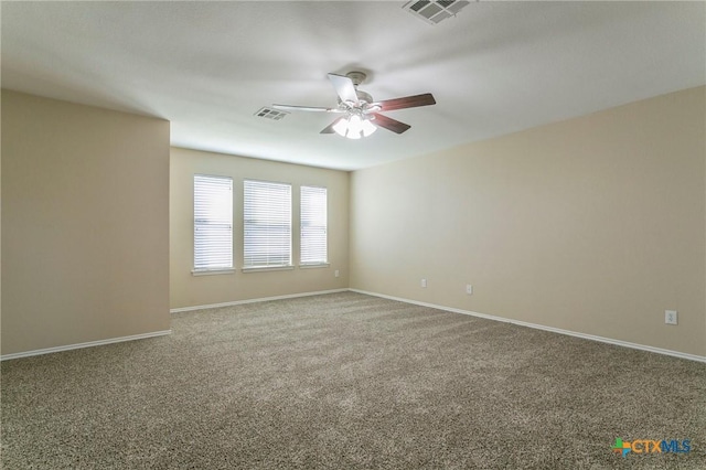 carpeted spare room with ceiling fan, visible vents, and baseboards