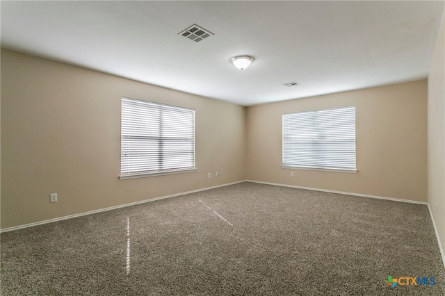 spare room featuring carpet flooring, visible vents, and baseboards