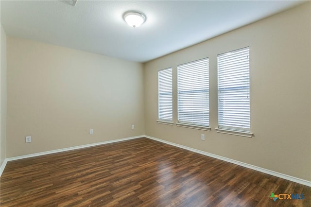 spare room with dark wood-style floors and baseboards