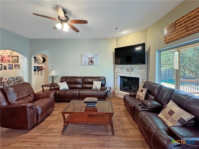 living room with ceiling fan, a fireplace, and light wood-type flooring