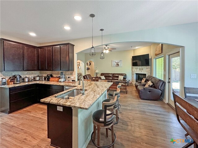 kitchen with pendant lighting, sink, a kitchen breakfast bar, dark brown cabinetry, and light hardwood / wood-style floors