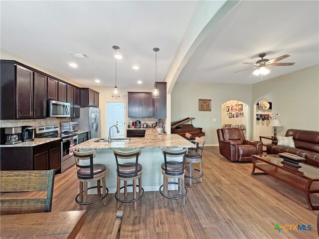 kitchen featuring a kitchen bar, sink, hanging light fixtures, appliances with stainless steel finishes, and backsplash