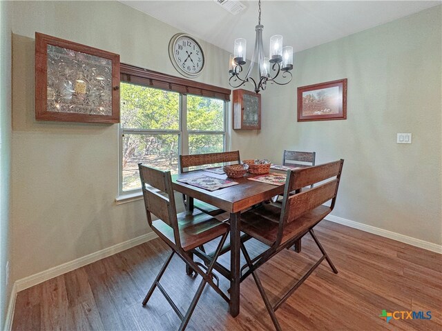 dining space featuring hardwood / wood-style floors and a chandelier