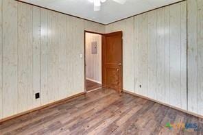 116 N Ben Wilson St, Victoria, TX 77901 - spare room featuring wood finished floors, wooden walls, and ceiling fan