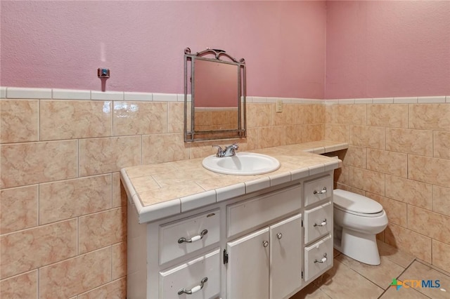 116 N Ben Wilson St, Victoria, TX 77901 - half bathroom featuring vanity, tile walls, tile patterned flooring, and a wainscoted wall