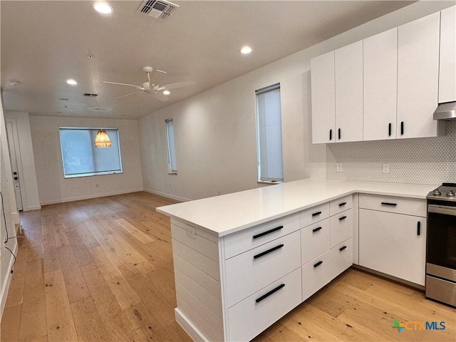 kitchen featuring white cabinets, light wood-type flooring, kitchen peninsula, and electric stove