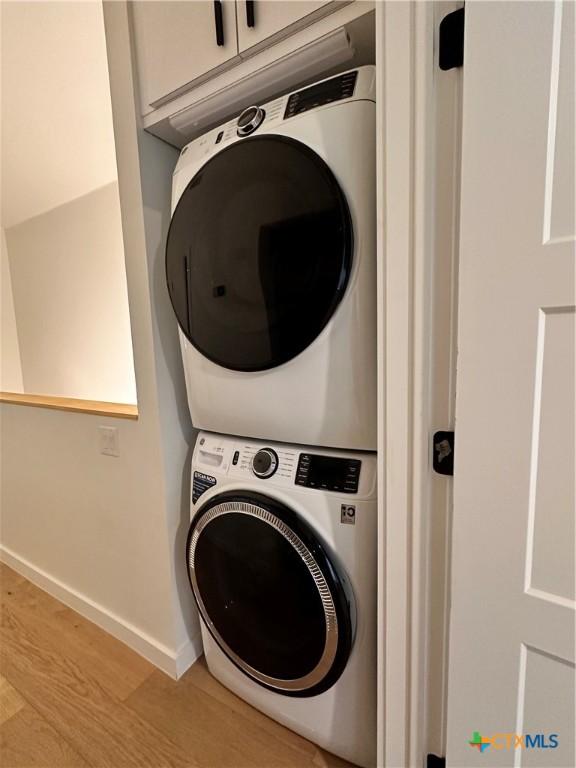 laundry room with stacked washer and dryer and hardwood / wood-style floors