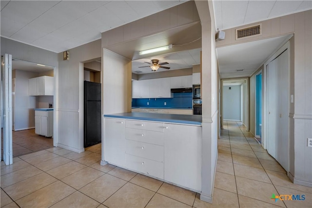 kitchen featuring light tile patterned floors, visible vents, freestanding refrigerator, ceiling fan, and white cabinetry