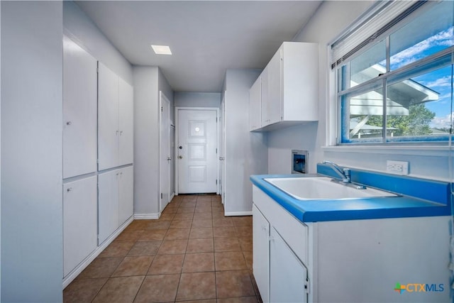 kitchen with baseboards, a sink, tile patterned flooring, light countertops, and white cabinets