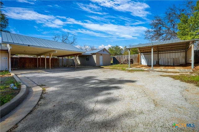 exterior space with a carport, fence, an outbuilding, and driveway