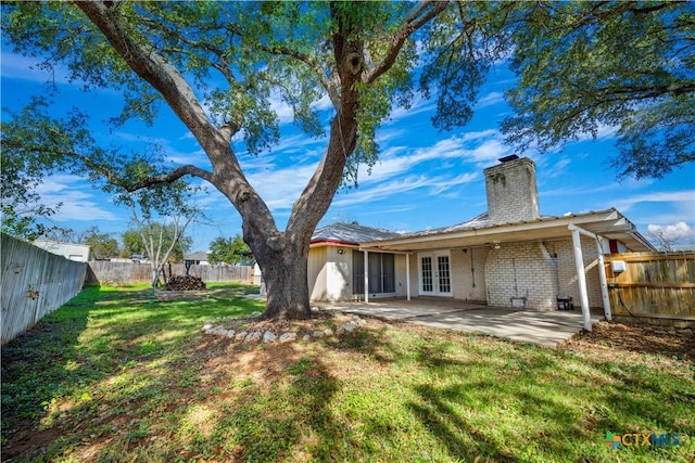 rear view of property with a patio, a fenced backyard, french doors, a yard, and brick siding