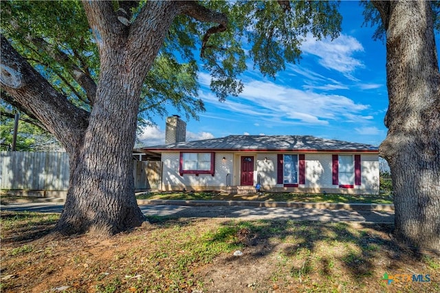 ranch-style home featuring a chimney and fence