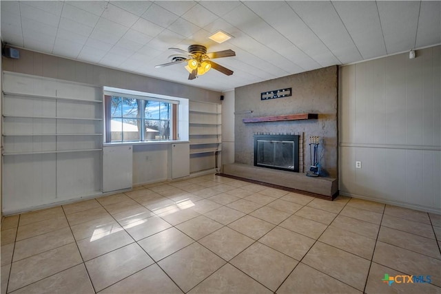 unfurnished living room featuring light tile patterned floors, a brick fireplace, a ceiling fan, and built in shelves