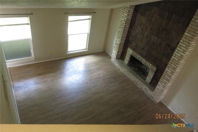 2101 Stagecoach Trl, Temple, TX 76502 - unfurnished living room with wood finished floors, a textured ceiling, and a fireplace