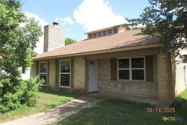 2101 Stagecoach Trl, Temple, TX 76502 - view of front facade featuring brick siding, a chimney, roof with shingles, and a front yard