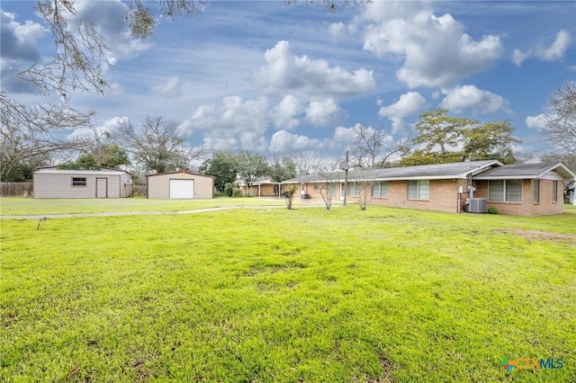 view of yard featuring a garage, central AC, and an outdoor structure