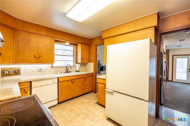 kitchen featuring sink, white appliances, and tasteful backsplash