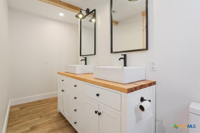413 S Tyler St, Mcgregor, TX 76657 - bathroom with baseboards, wood finished floors, double vanity, toilet, and recessed lighting