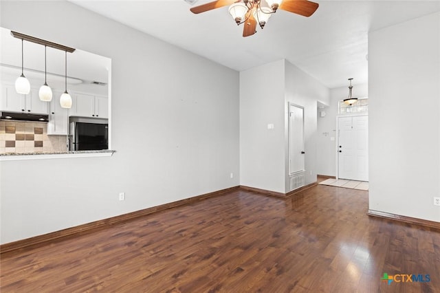 unfurnished living room featuring ceiling fan and dark wood-type flooring