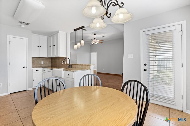 tiled dining room with ceiling fan and sink