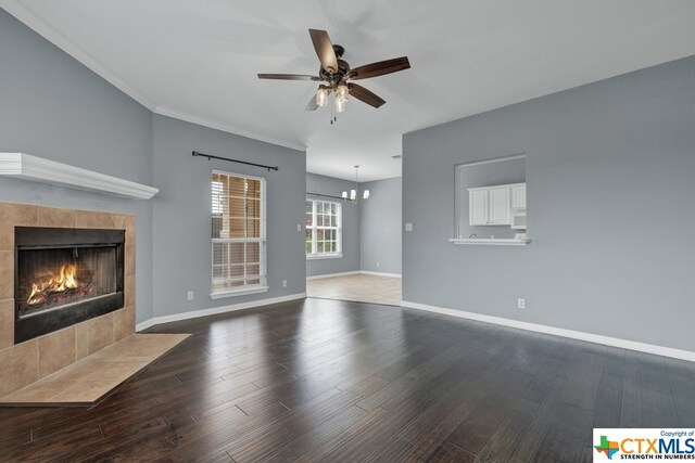 unfurnished living room featuring a tile fireplace, ceiling fan with notable chandelier, hardwood / wood-style flooring, and crown molding