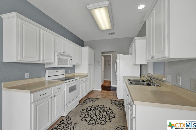 kitchen featuring light tile patterned floors, white appliances, white cabinetry, and sink