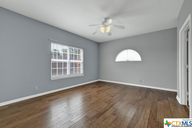 empty room with dark wood-type flooring and ceiling fan