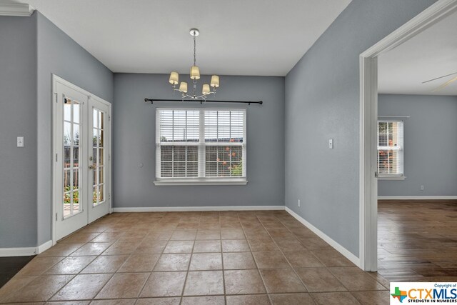 unfurnished dining area featuring french doors, wood-type flooring, a healthy amount of sunlight, and a chandelier