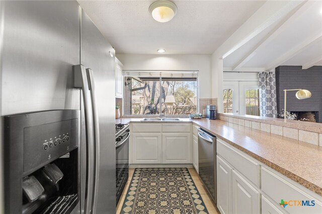 5004 Powder River Rd, Austin, TX 78759 - kitchen featuring light countertops, light tile patterned floors, white cabinets, stainless steel appliances, and a sink