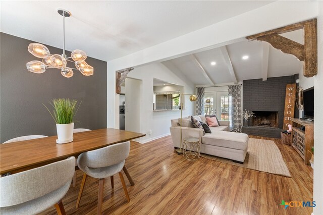 5004 Powder River Rd, Austin, TX 78759 - living room featuring baseboards, lofted ceiling with beams, light wood-style floors, a brick fireplace, and a chandelier