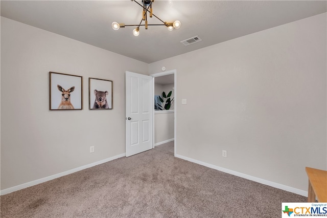 carpeted spare room featuring a chandelier