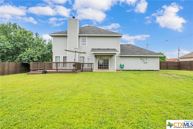 rear view of property featuring a lawn and a deck