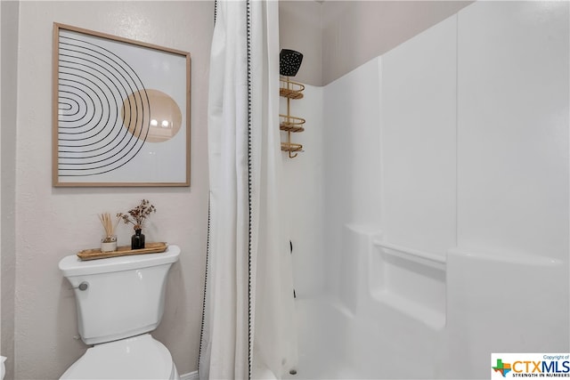 bathroom featuring curtained shower and toilet