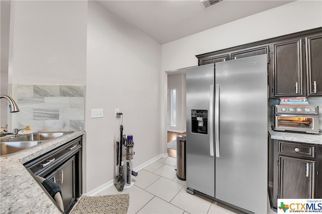 kitchen with light stone counters, stainless steel fridge with ice dispenser, dark brown cabinetry, light tile patterned floors, and sink