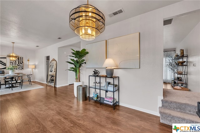 hall featuring dark wood-type flooring and a notable chandelier