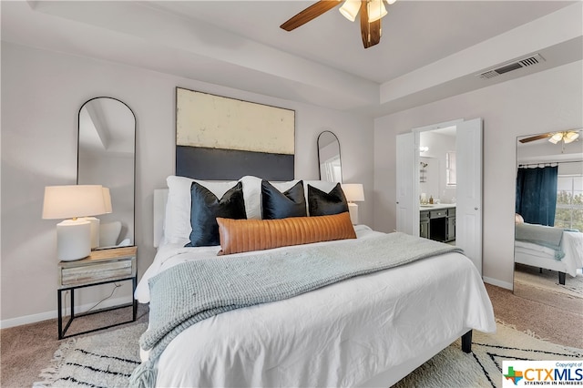 bedroom with ensuite bath, light carpet, and ceiling fan