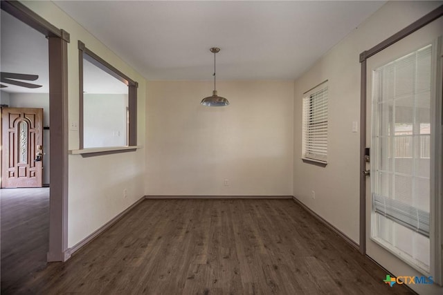 unfurnished dining area with baseboards, a ceiling fan, and dark wood finished floors